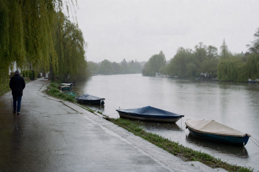 A quiet upper reach of the Thames on a still morning, green banks and moored skiffs, mist lying low over flat water